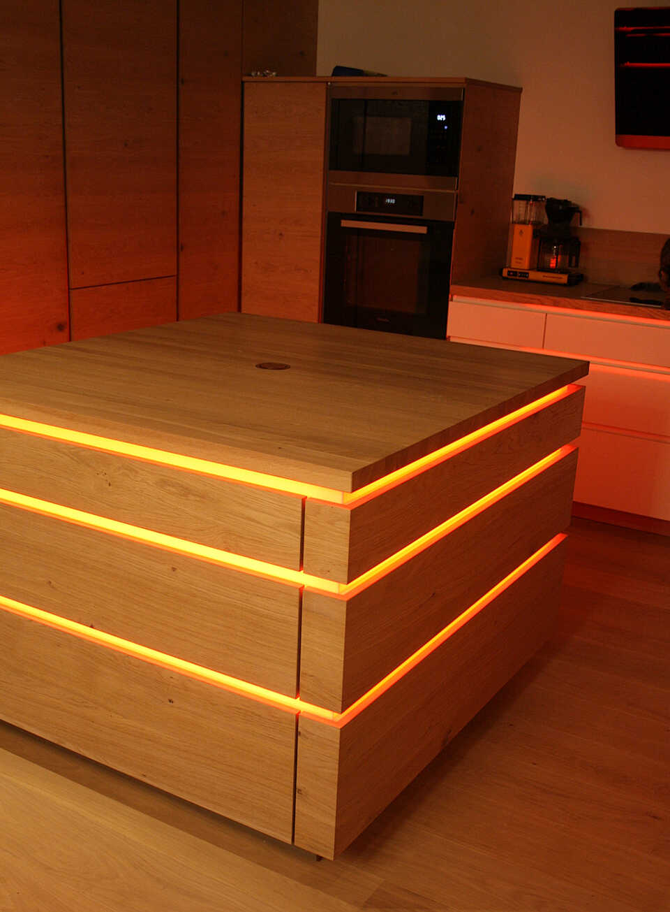Küchenblock mit Leuchtelementen in gelb / orange und geschlossenen Schubladen.
